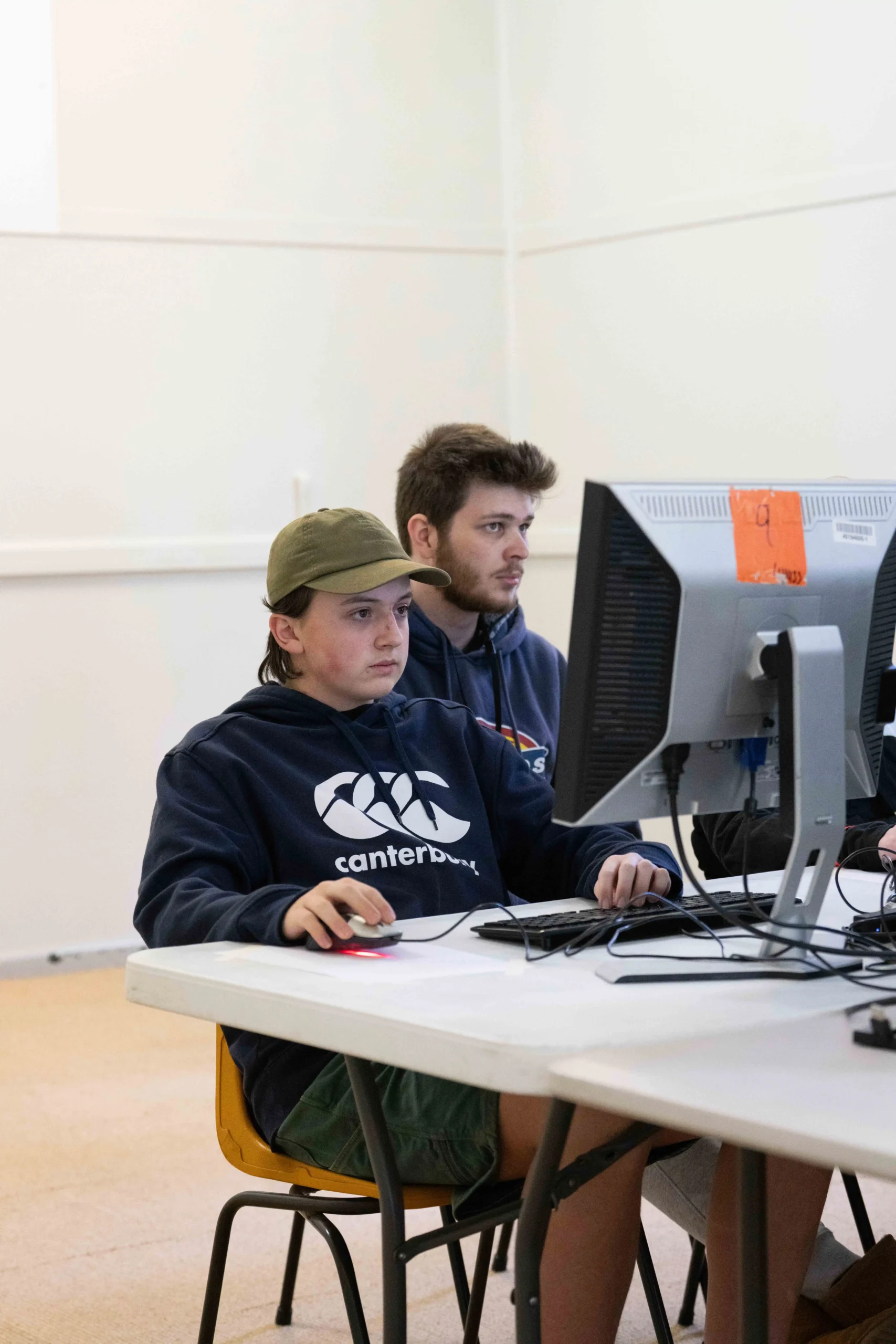 A CrüTech leader helping campers at a computer during an elective